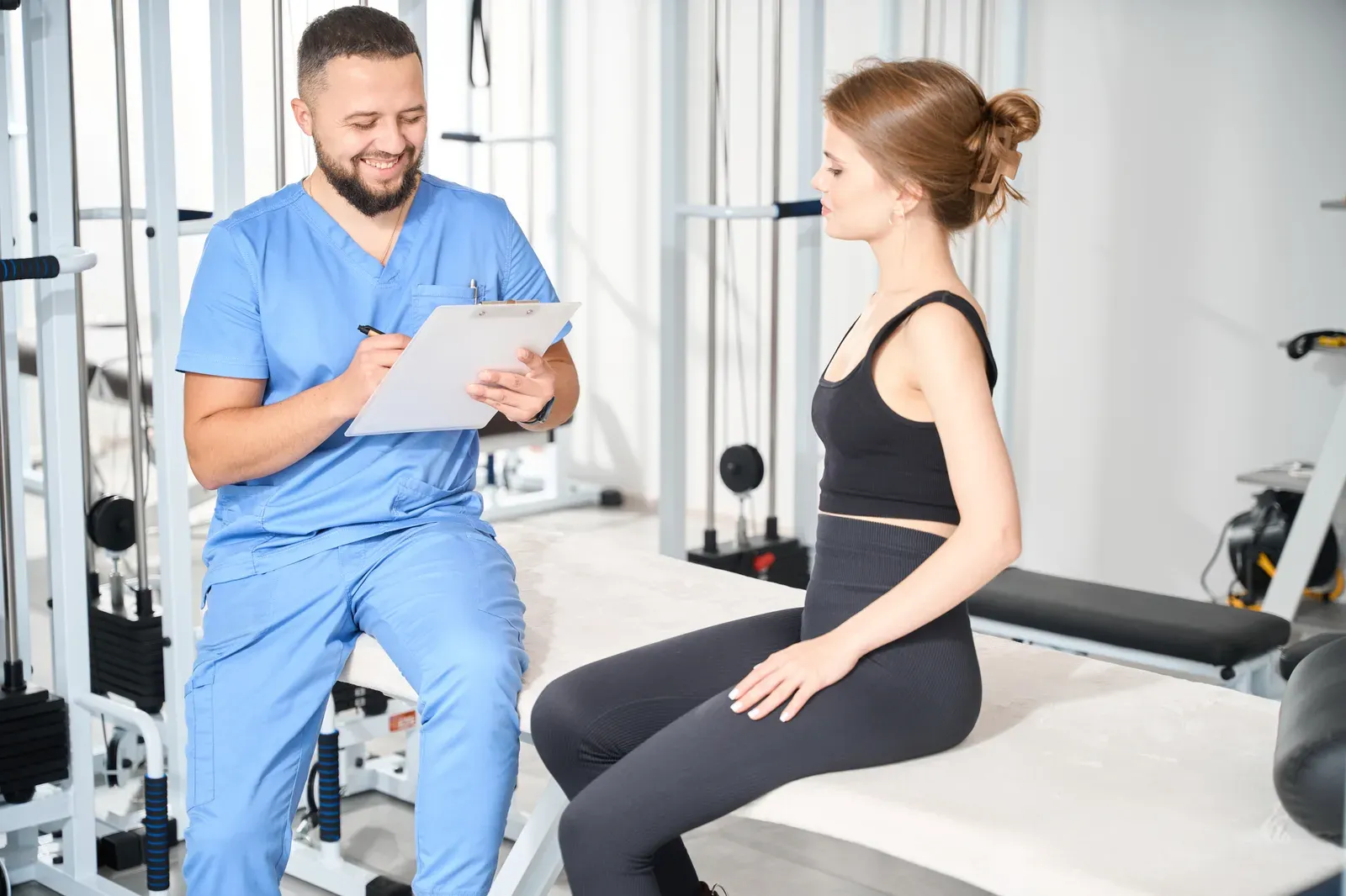 Two people in a gym office talking through a list of written questions