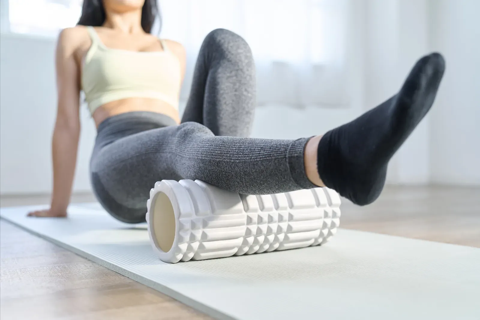 Woman using a foam roller behind her knees on a recovery day