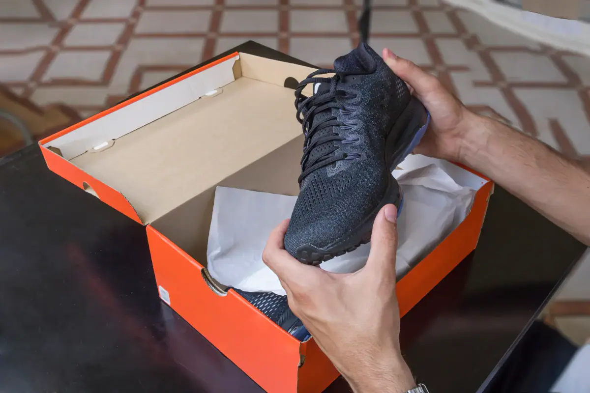 Hands lifting a fresh training shoe from its shoebox