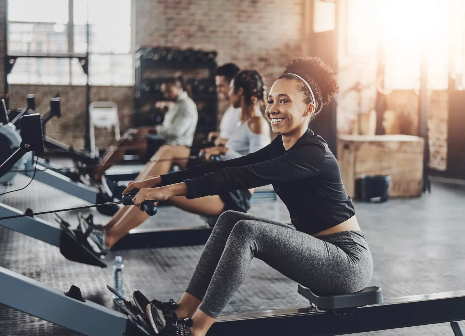 Woman on a rowing machine in a gym class, one of the cardio options to weigh against the treadmill