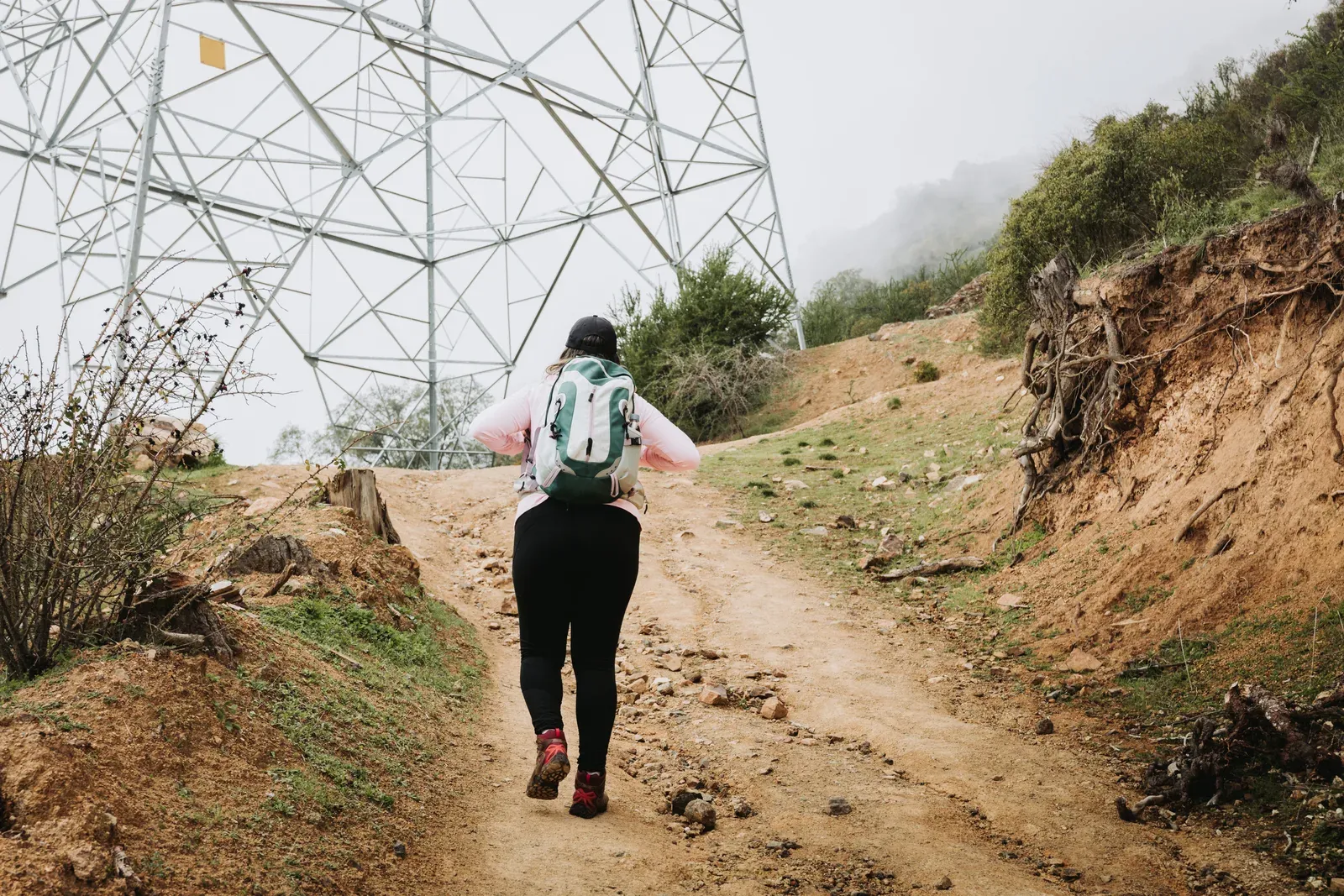 A woman with a loaded backpack hiking up a hill on a rucking walk