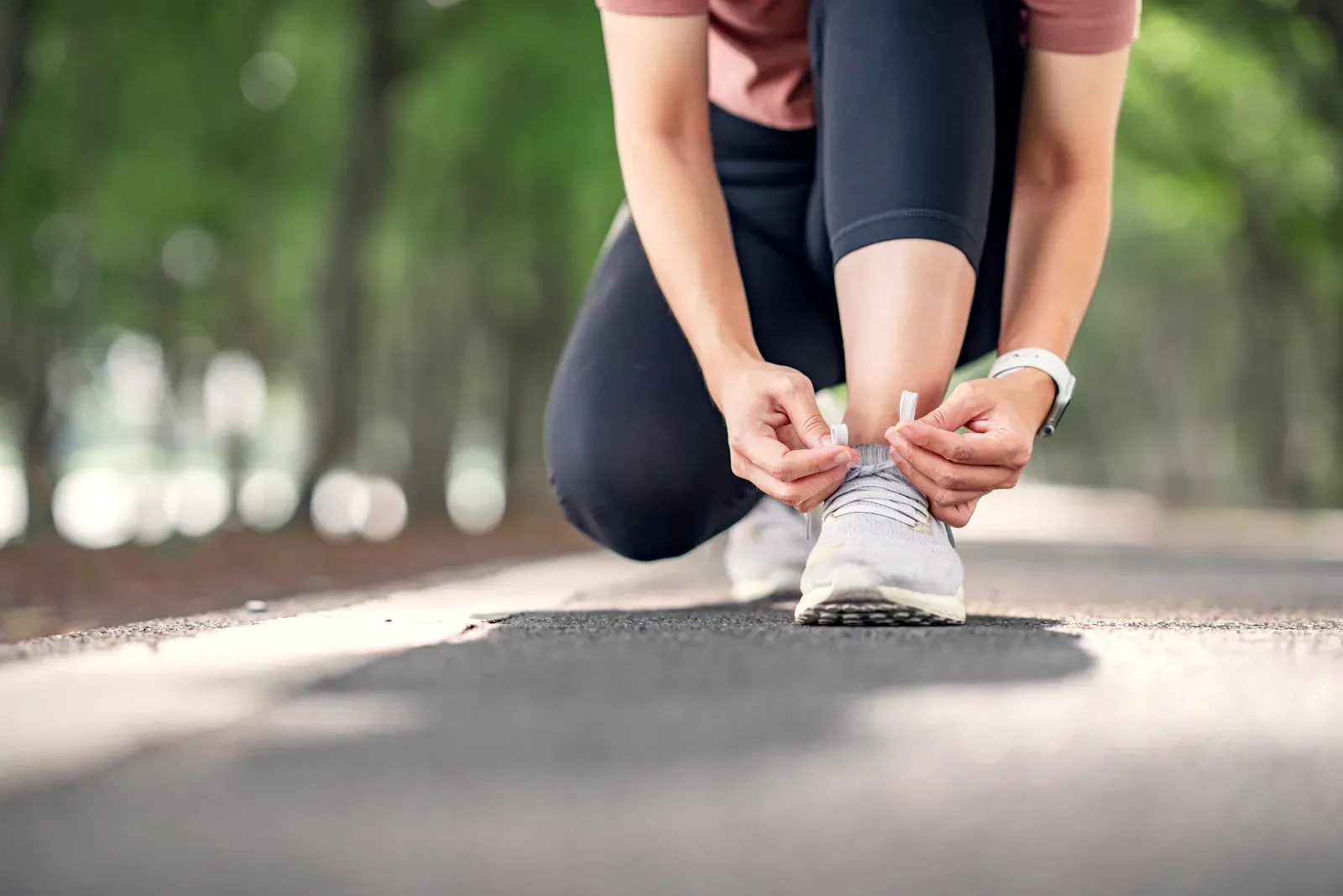 Woman runner tying her shoe laces in a forest park before a run, a start for running on a GLP-1