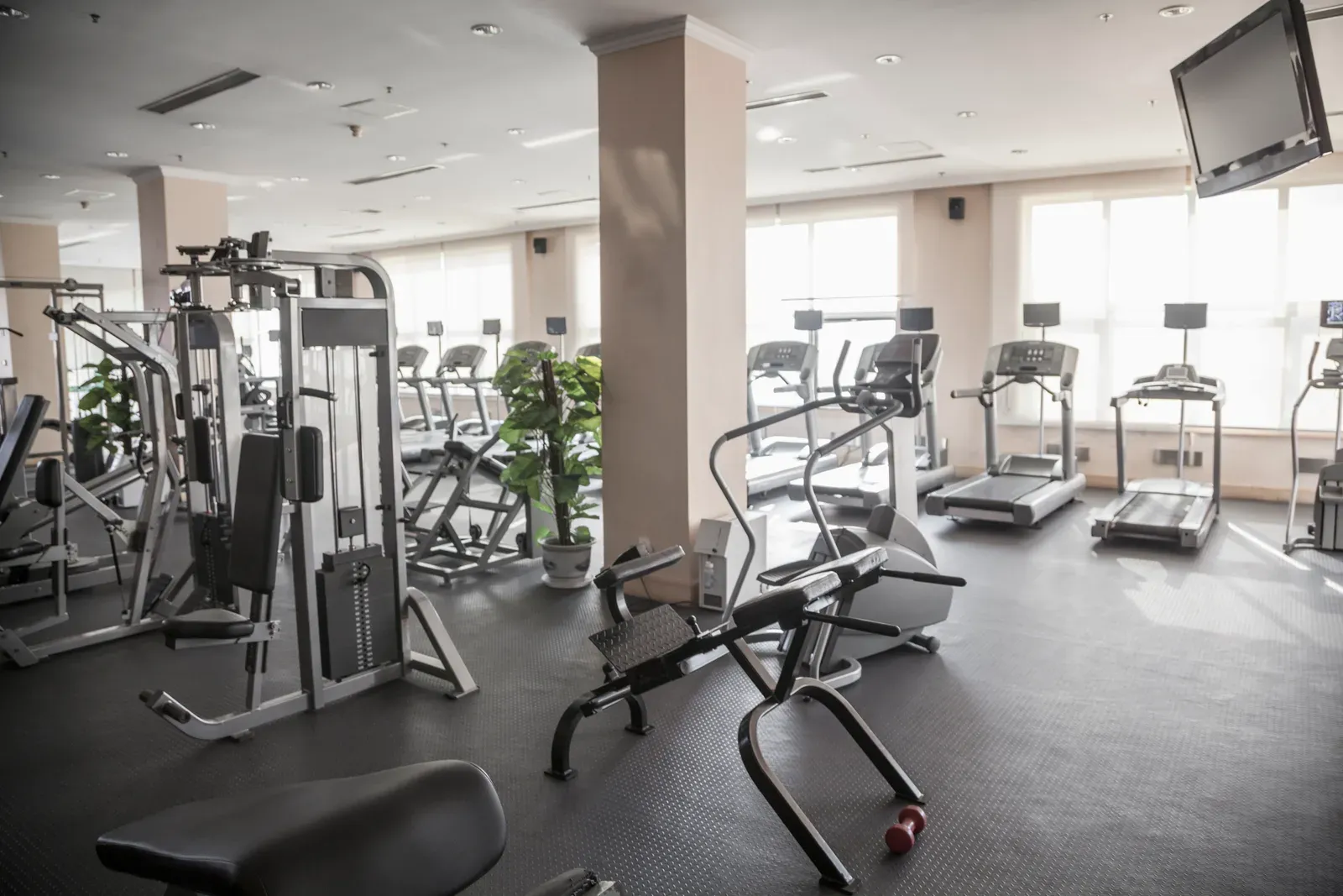 Parent training with a coach in an empty, sunlit private gym on a weekday morning