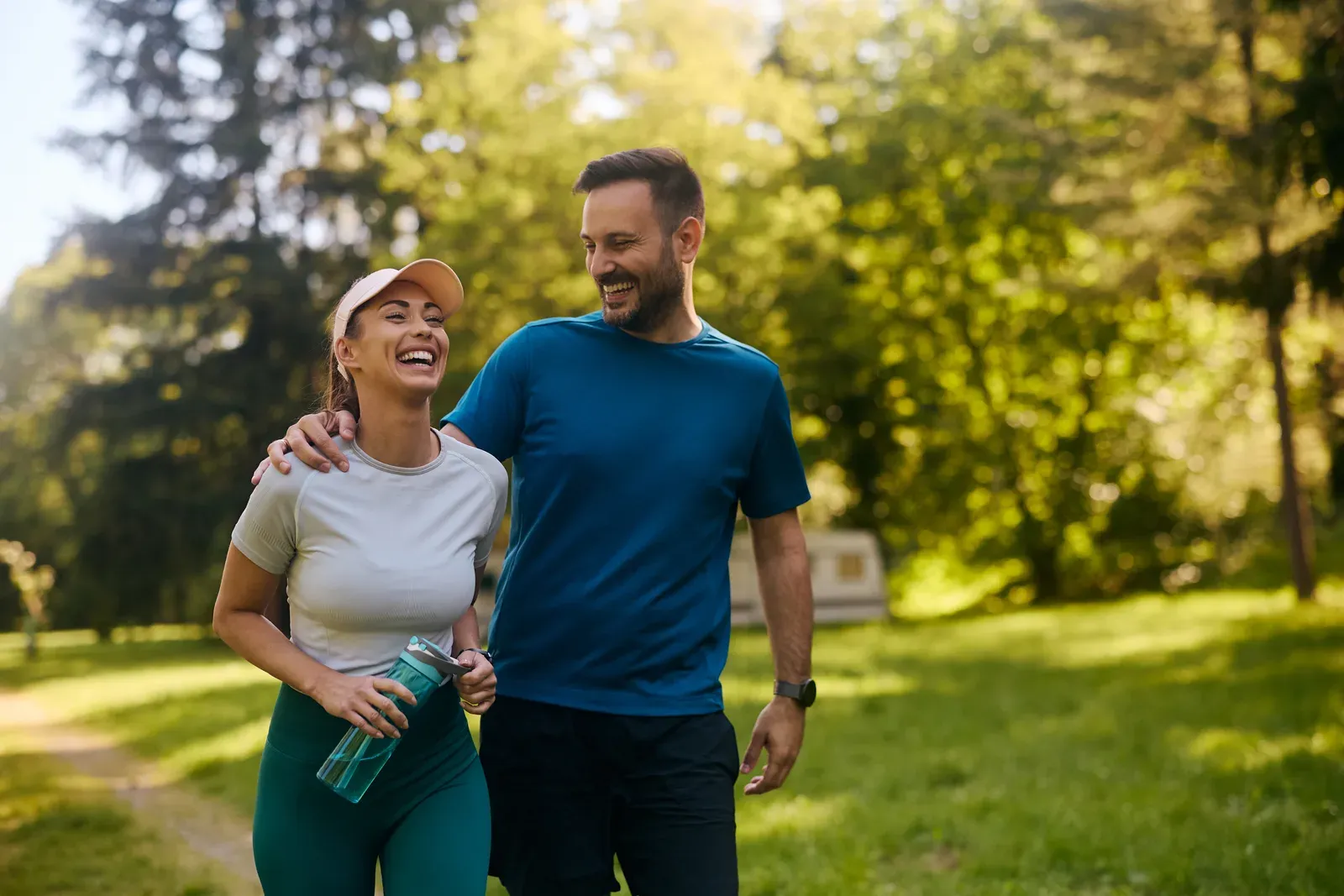 Happy couple laughing through a workout together in the park