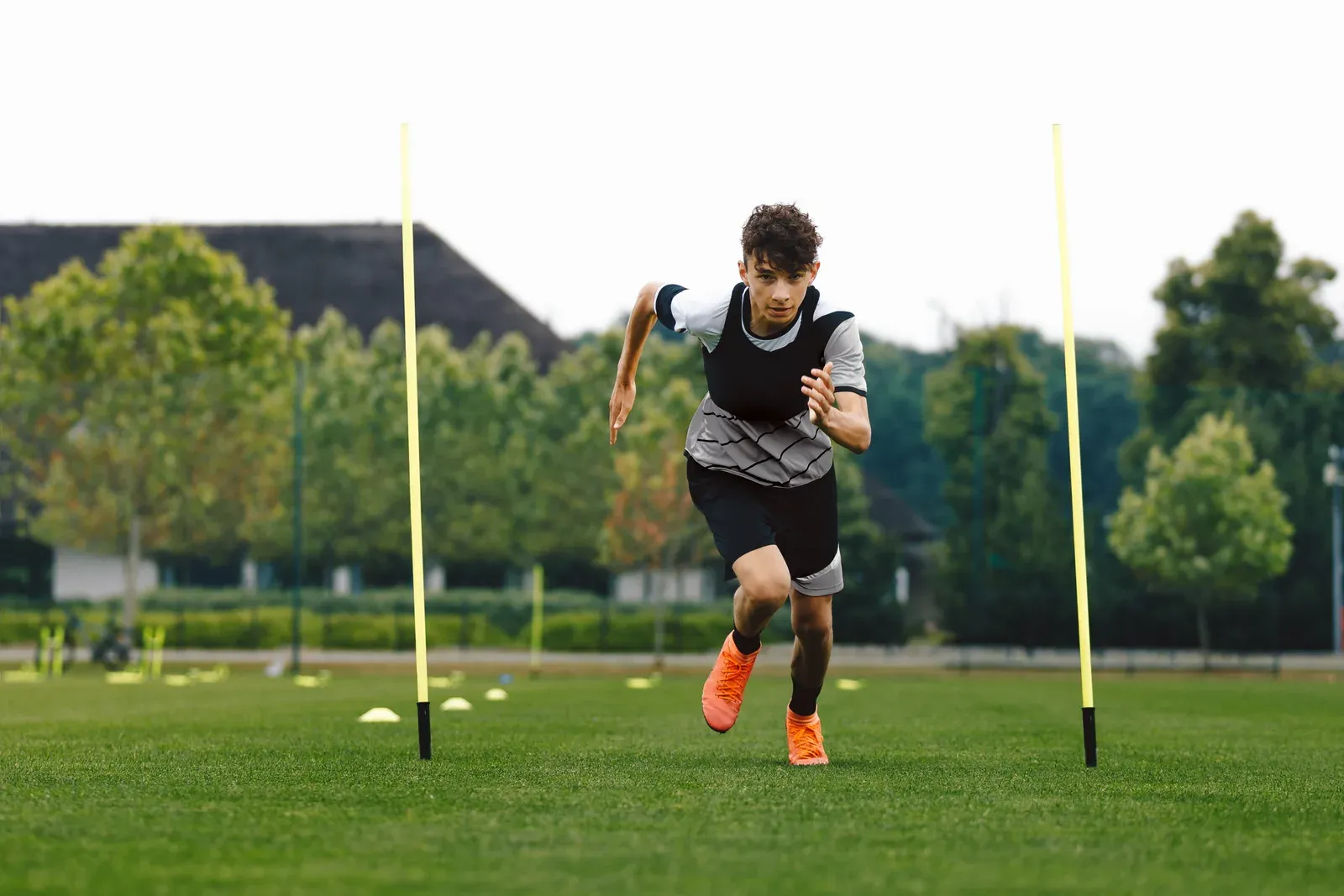 Young soccer player driving through a sprint drill on a training field with a ball ahead