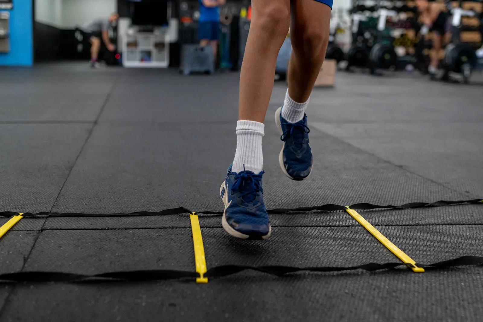 Athlete driving out of a coached sprint start inside a training facility