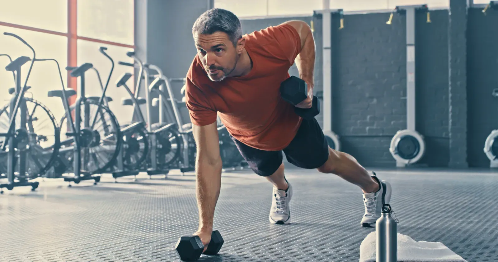 Mature man working with dumbbells in the gym, building strength after 40