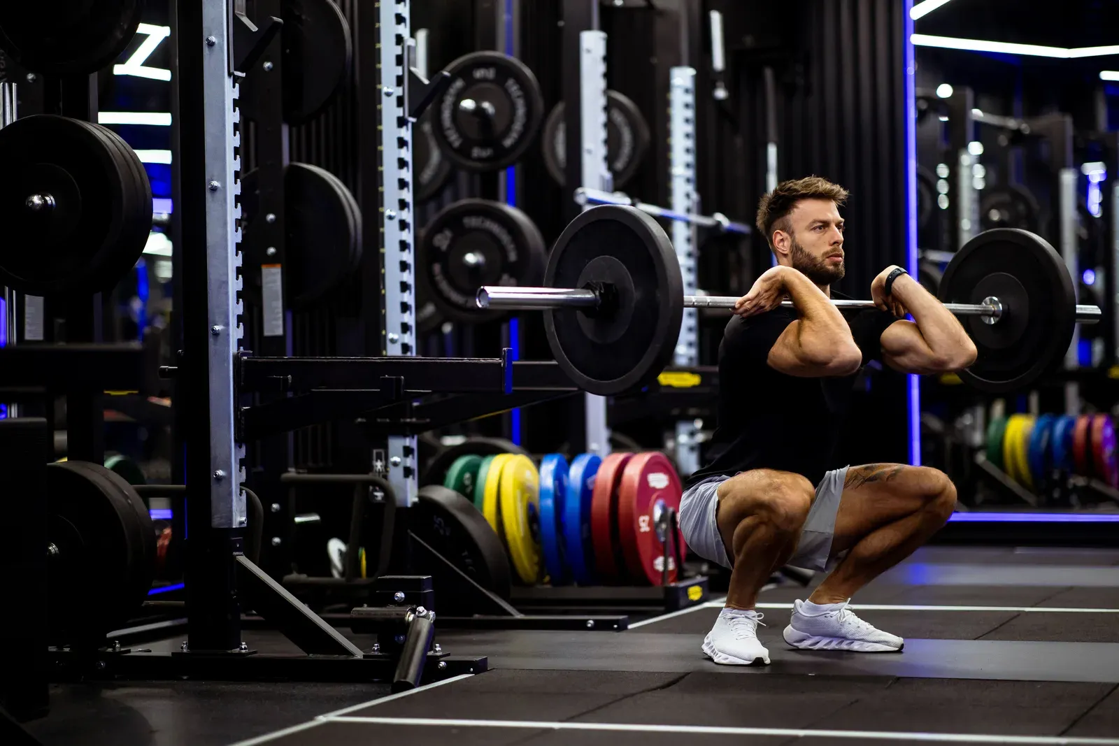 Coach checking a lifter's barbell setup and position during a squat
