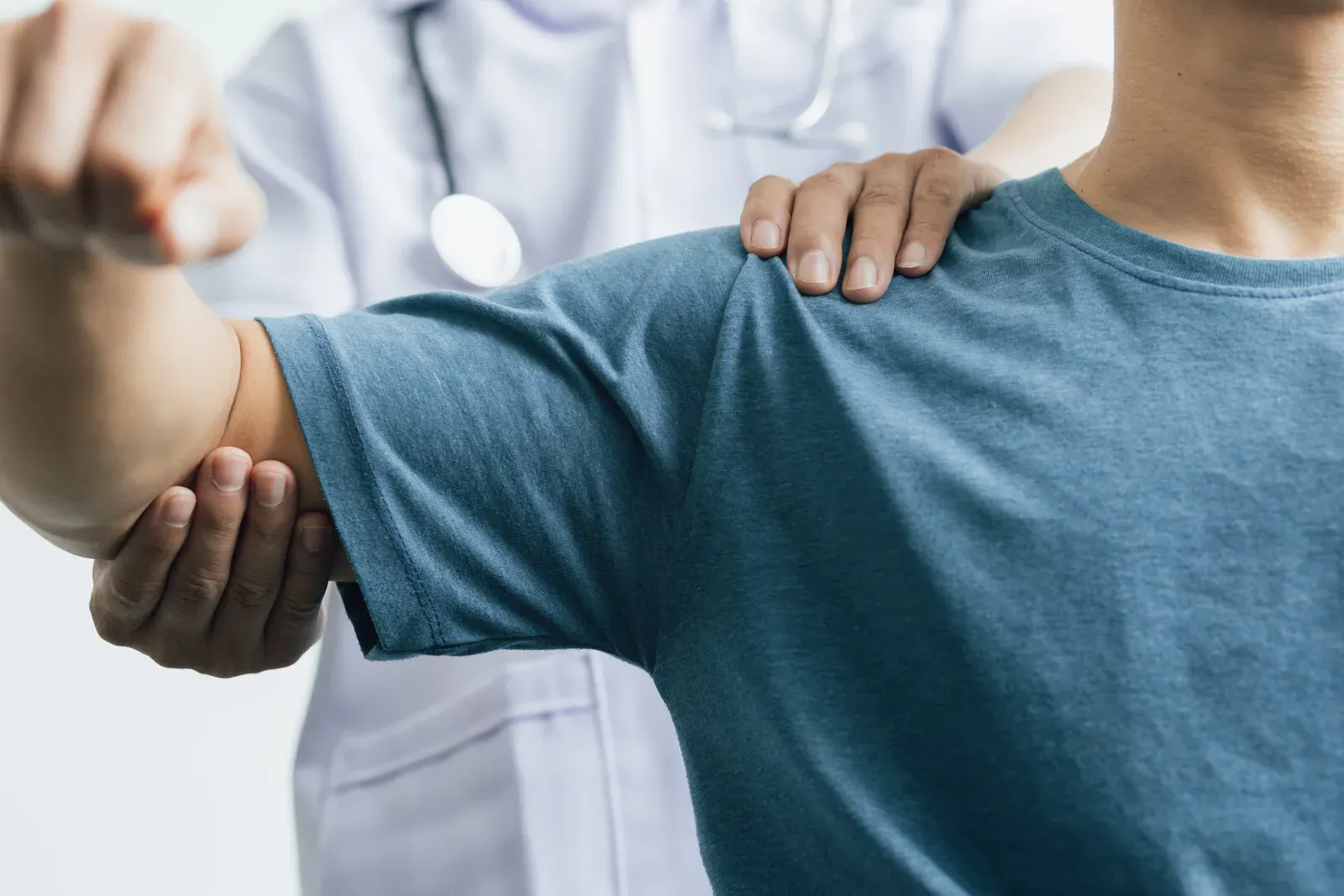 Doctor assessing a man's shoulder pain during a physical therapy consultation