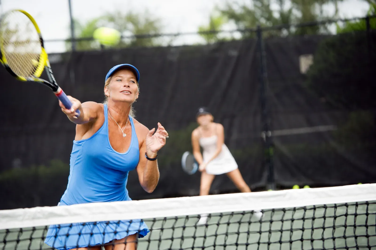 A tennis player in her 40s hitting a backhand on an outdoor court