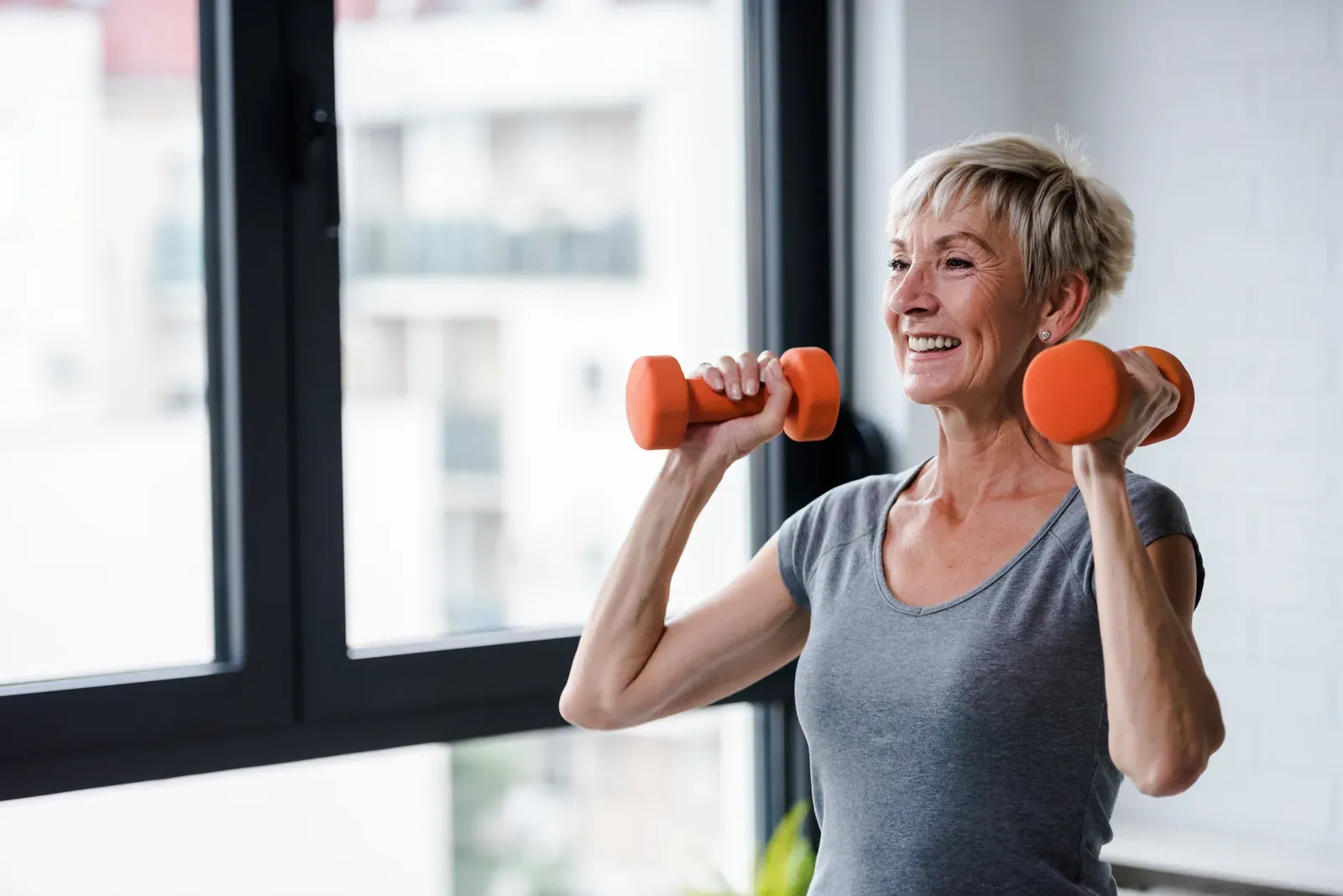 A woman in her 70s lifting dumbbells with steady focus