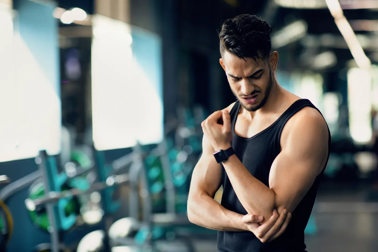 Man holding the outside of his elbow during a pause in a dumbbell workout