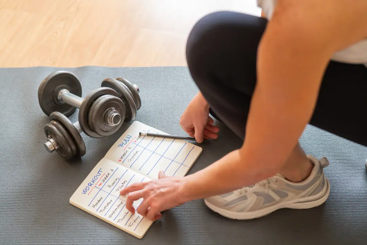 Runner sketching a six week race schedule in a notebook beside a pair of shoes