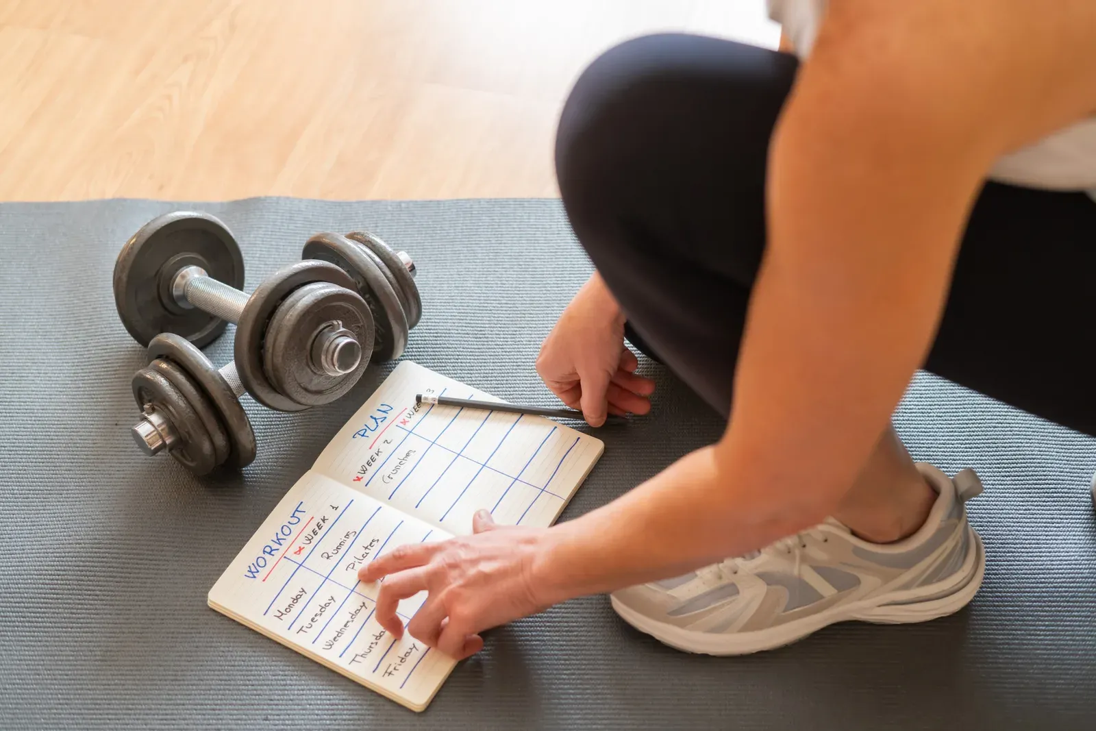 Professional reviewing a weekly calendar beside a packed travel bag and running shoes