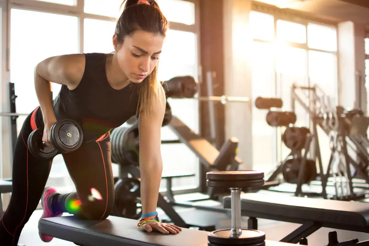 Athlete training with dumbbells in a softly lit gym before sunrise
