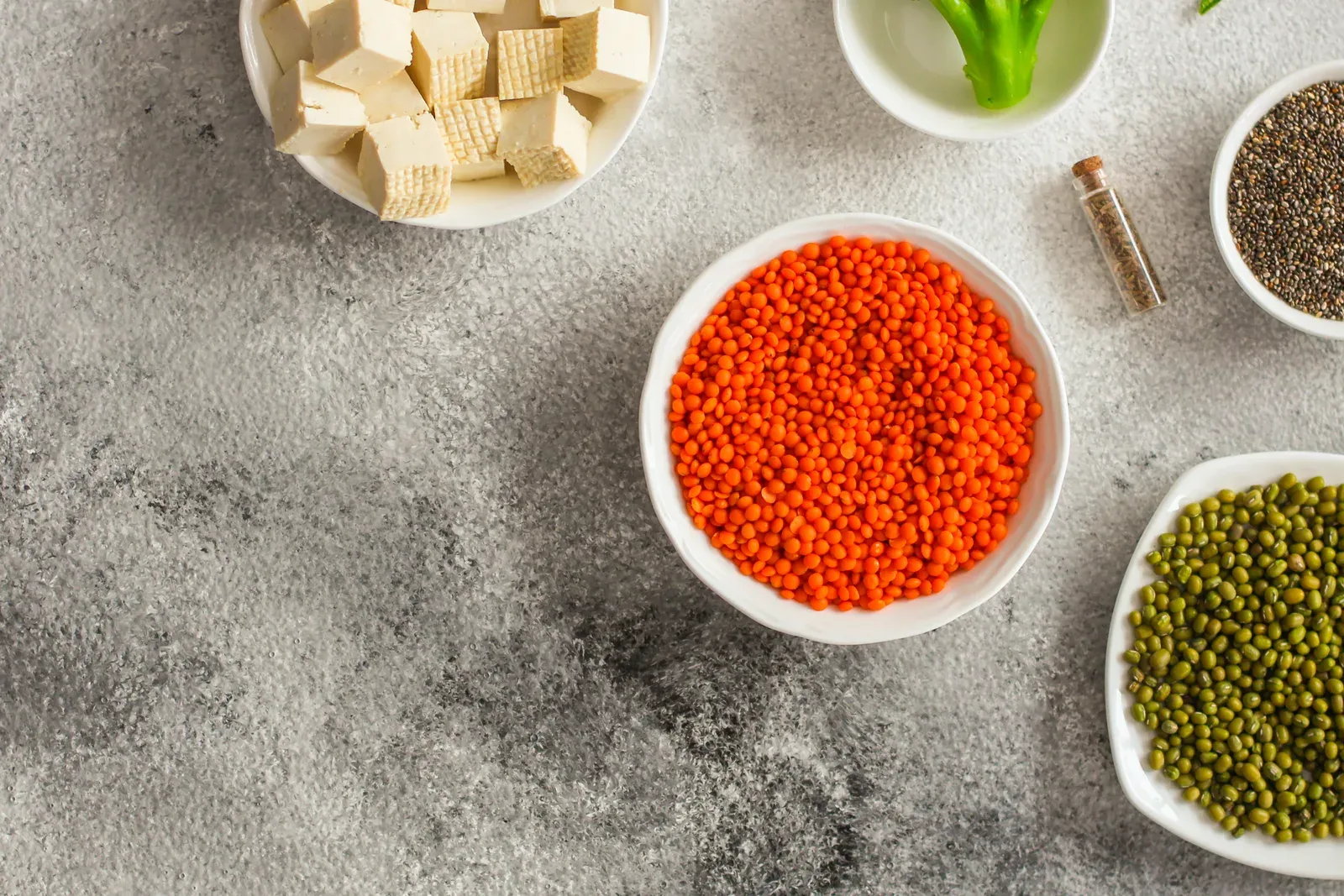 Bowls of lentils, beans, greens and other plant protein foods on a table