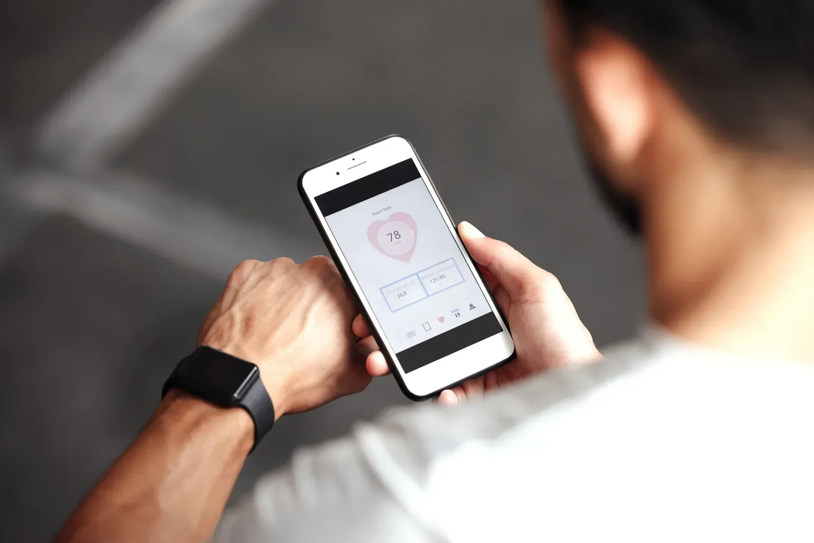 Checking heart rate and workout data on a smartwatch and phone at the gym