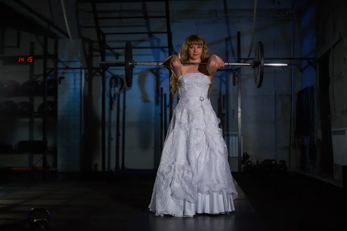 An engaged couple training together with dumbbells in a bright gym