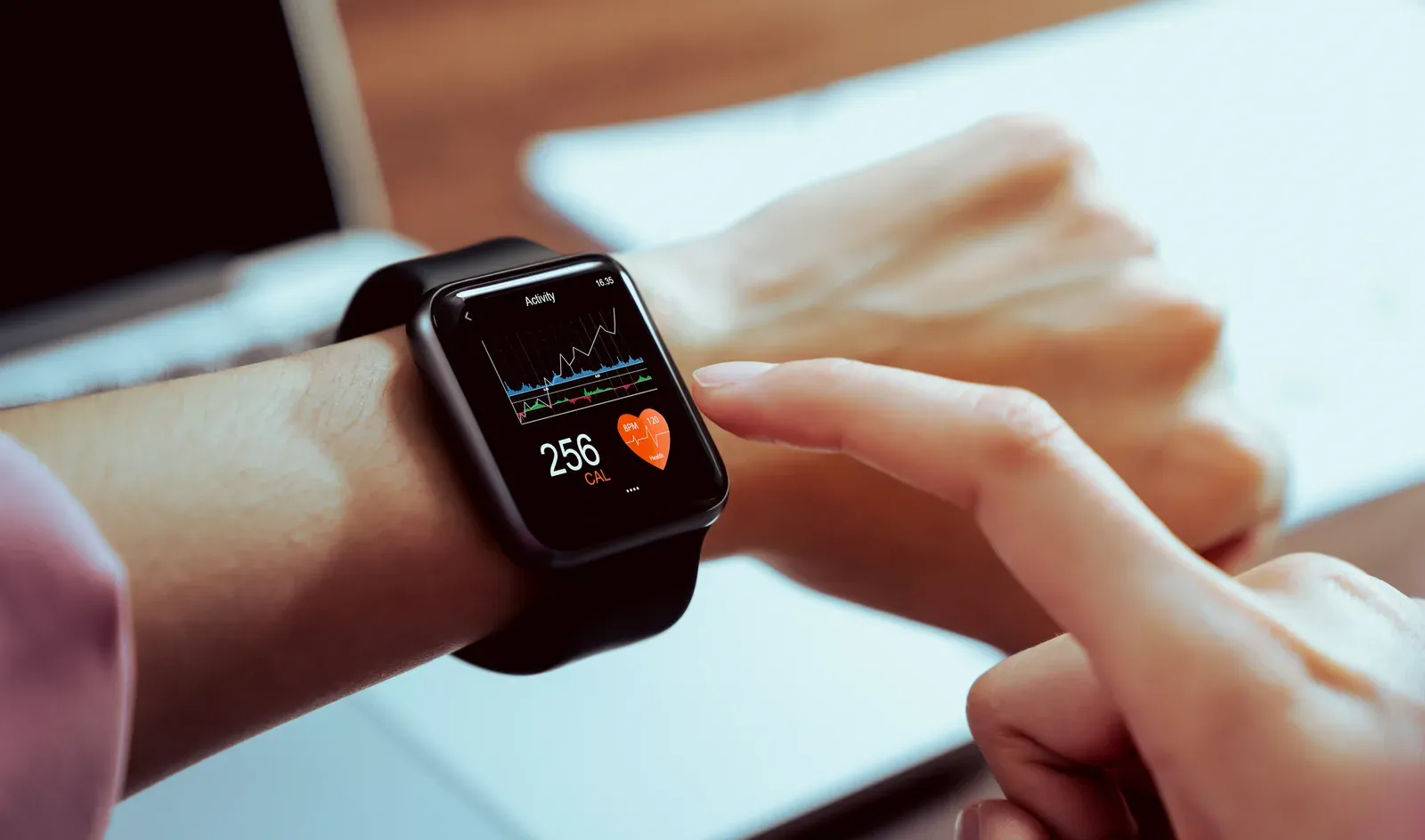 Hand touching a smartwatch showing a health tracking app