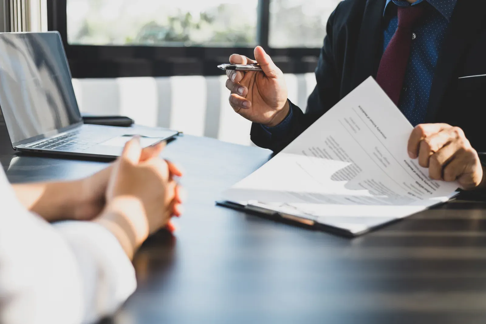 Businessman in a suit in his office pointing with a pen at where to sign, as in a training agreement
