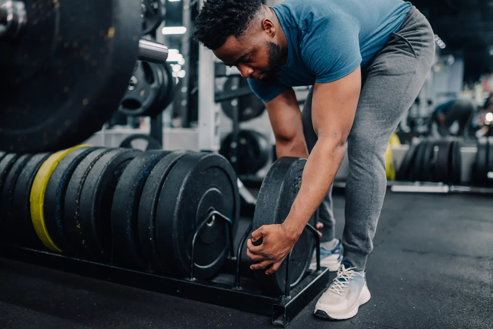 Young athlete preparing weights for his workout in the gym, a moment to decide when to add load
