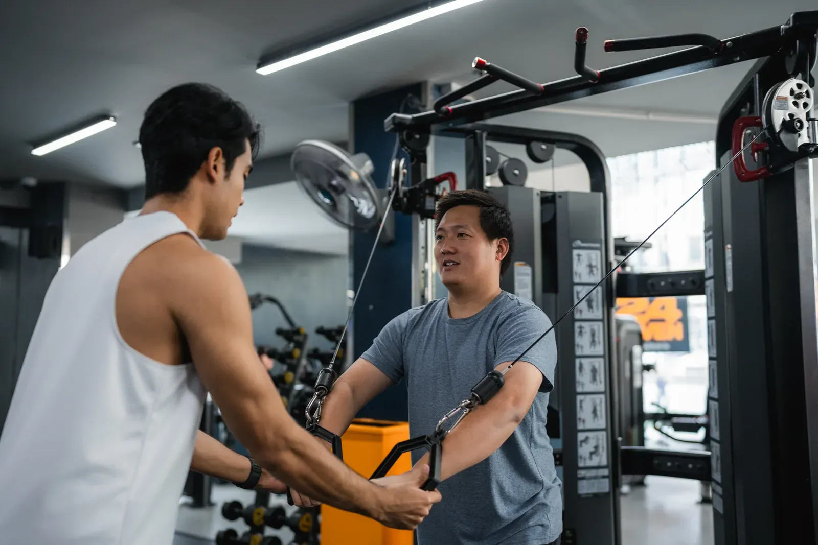 Larger-bodied man doing weight training with his fitness trainer at the gym, a starting point for major weight loss