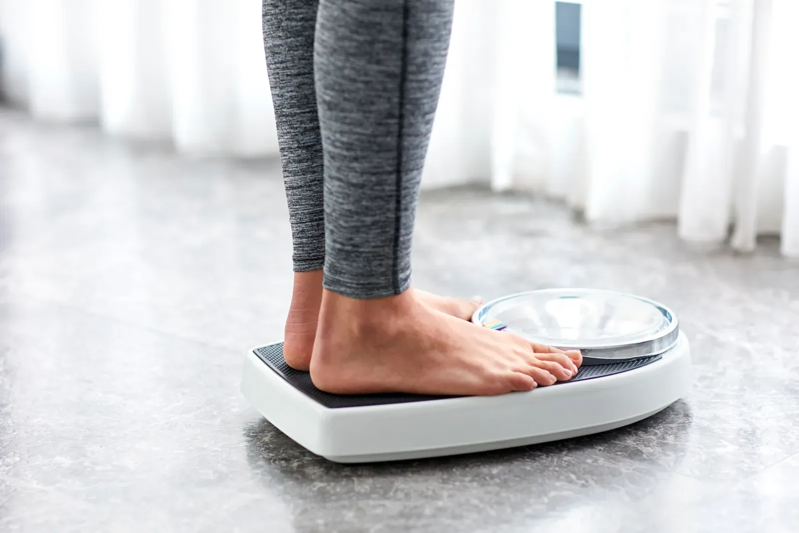 Young woman checking her day to day weight on home scales