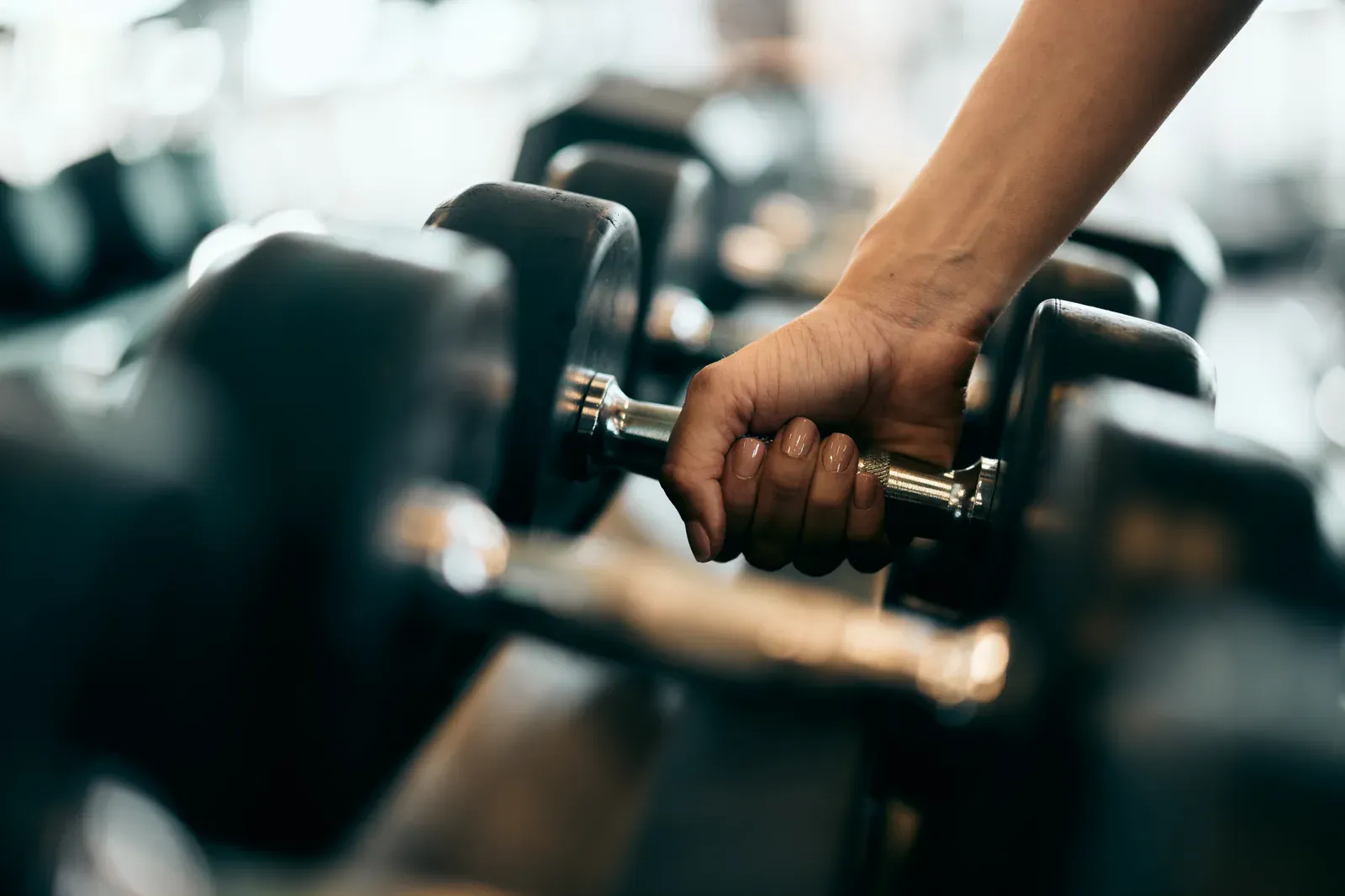 Woman's hand reaching down to pick up a heavy dumbbell