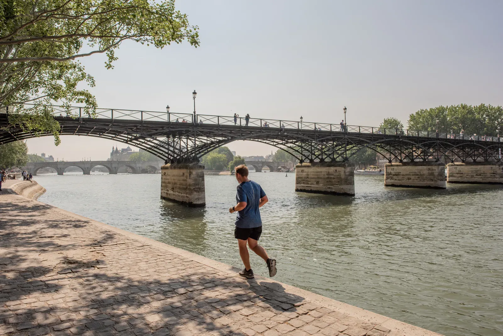 Man jogging on the quay along the Seine river in Paris, a run that could be one of two sessions a day