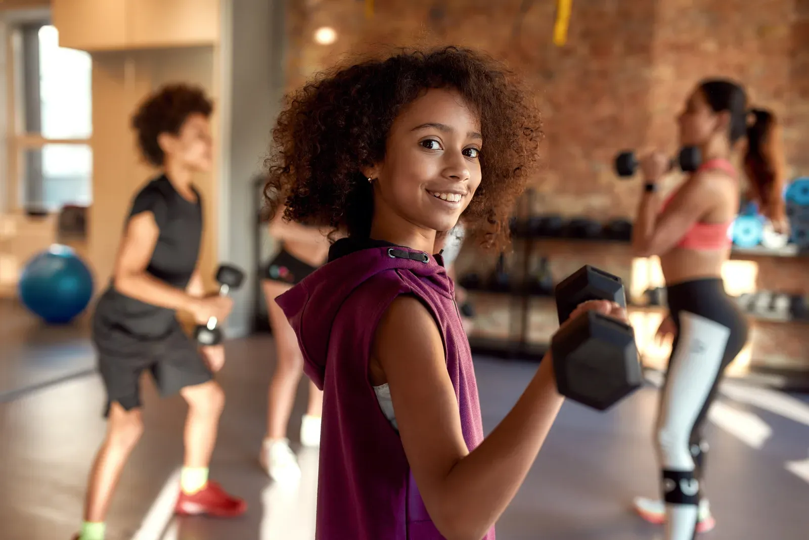Teenage athlete loading a barbell in a training room on a bright summer morning