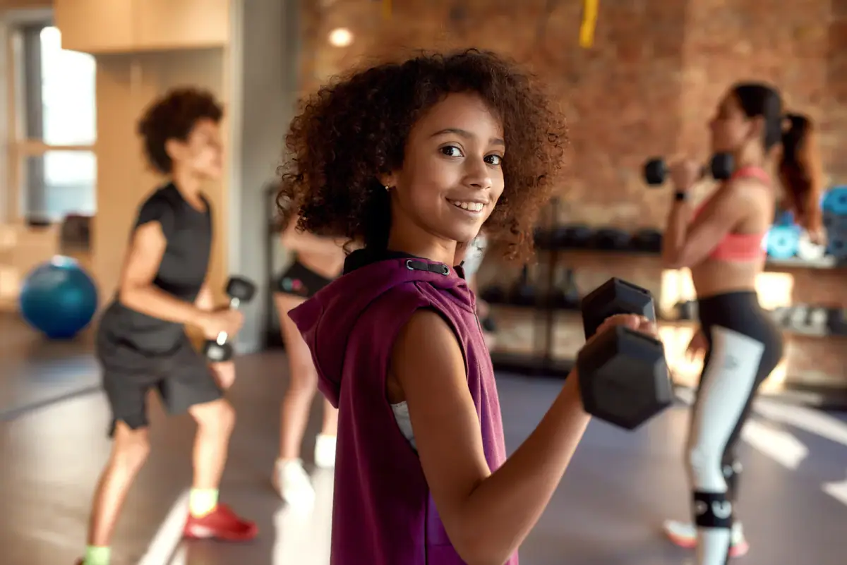 Teenage athlete loading a barbell in a training room on a bright summer morning